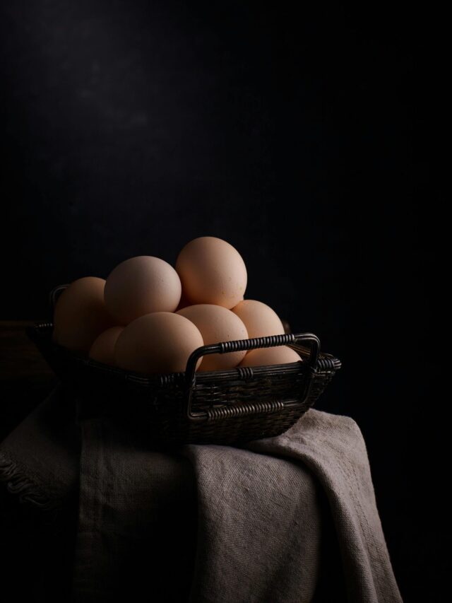 A rustic basket full of fresh eggs on a dark background, perfect for kitchen decor.