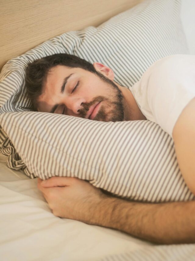 Man sleeping peacefully on striped bedding, embracing relaxation and comfort.