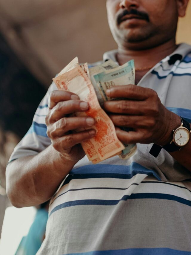 Man in Indian market counting rupee notes, showcasing daily street commerce.