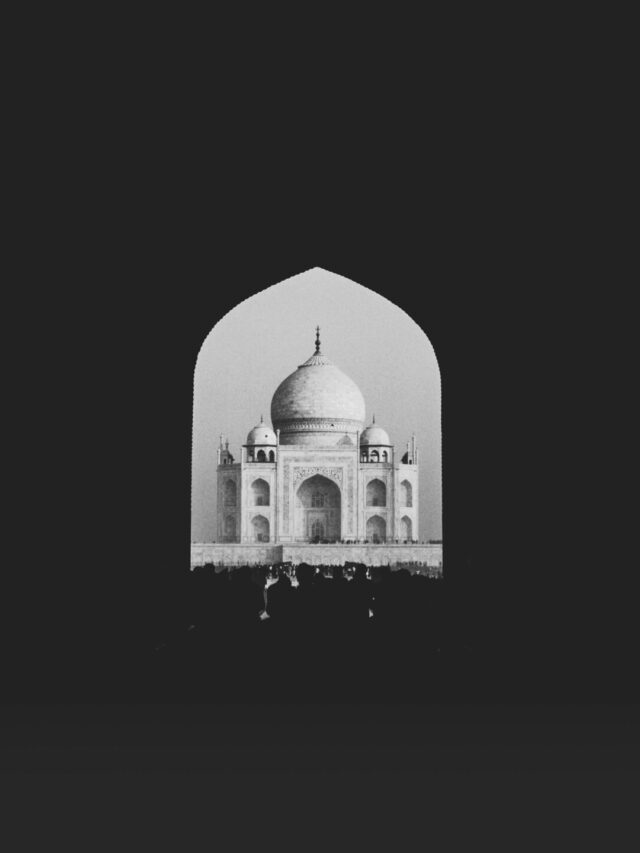 Black and white photo of the Taj Mahal framed by a dark archway, highlighting its beauty.