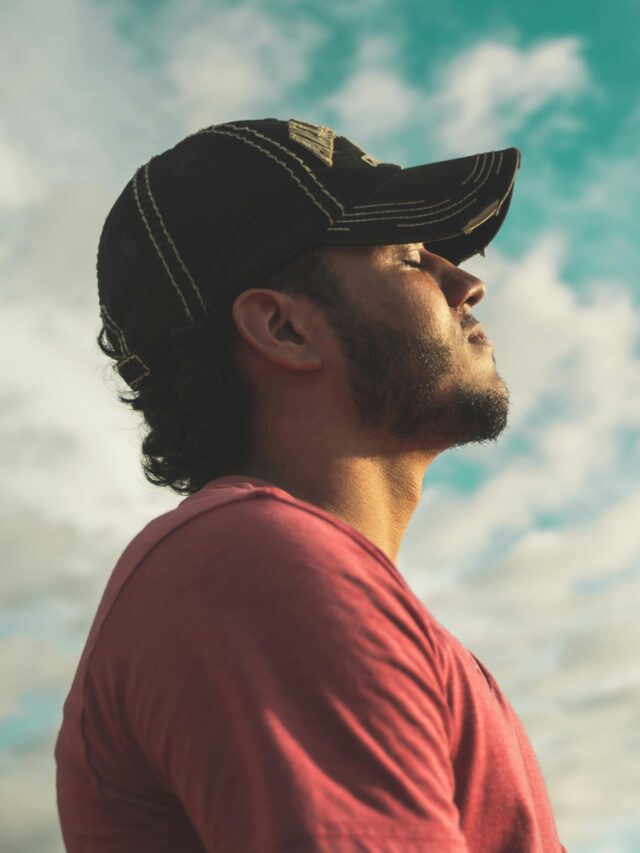 A man enjoys outdoor relaxation and mindfulness beneath a bright, cloudy sky, exuding calm and peace.
