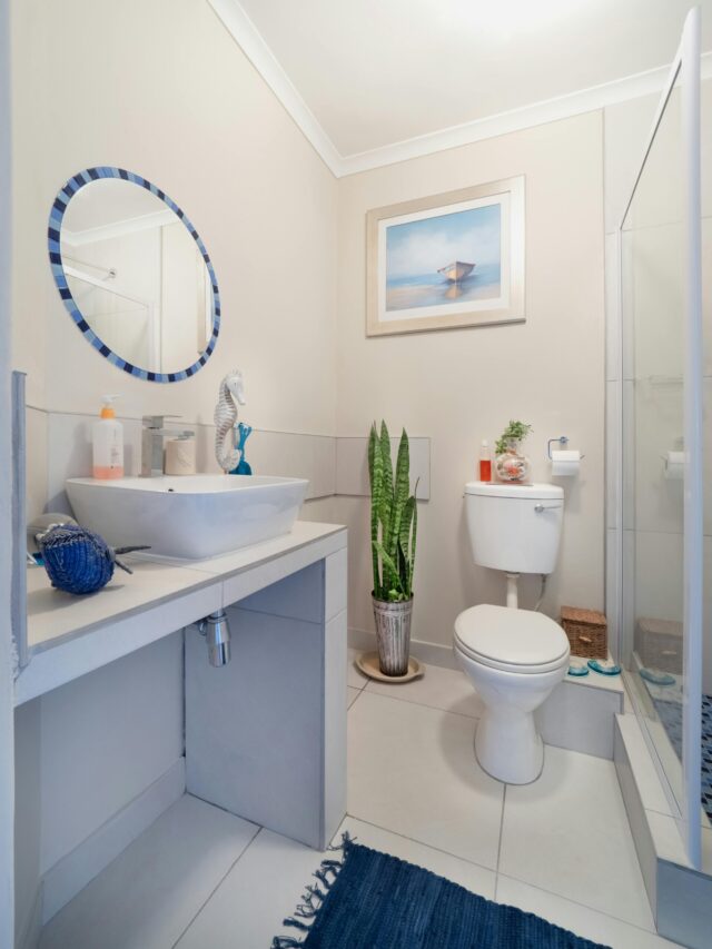 A clean, modern bathroom with white fixtures and minimalist decor, featuring a sink and toilet.