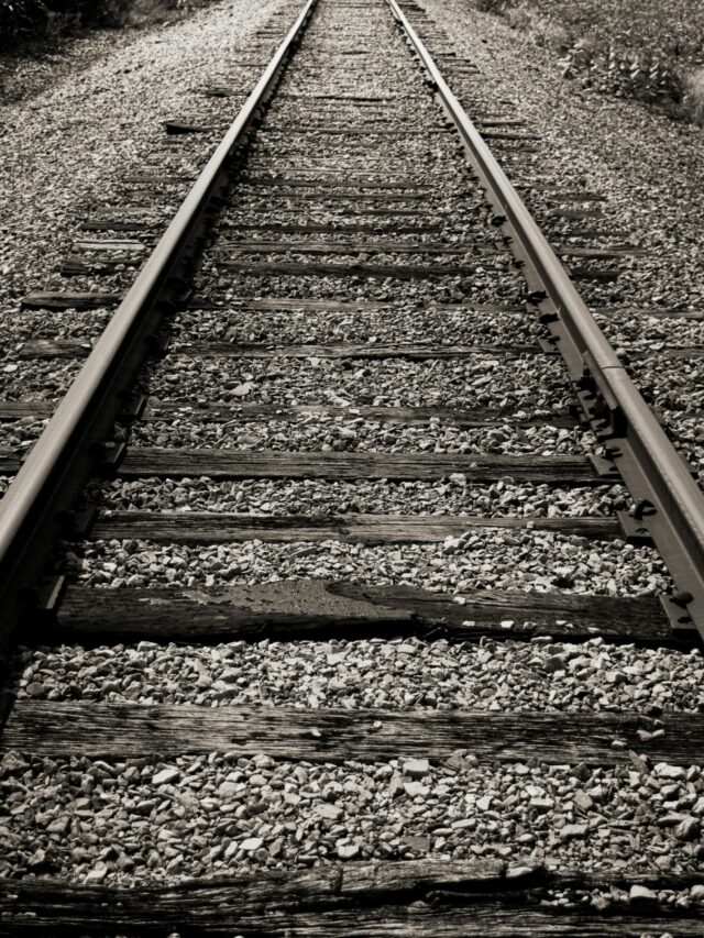 Black and white photo of rustic railroad tracks disappearing into the distance.