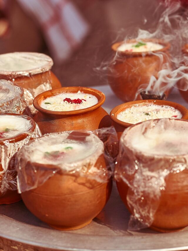 Steaming clay pots of traditional Indian lassi with vibrant garnishes.